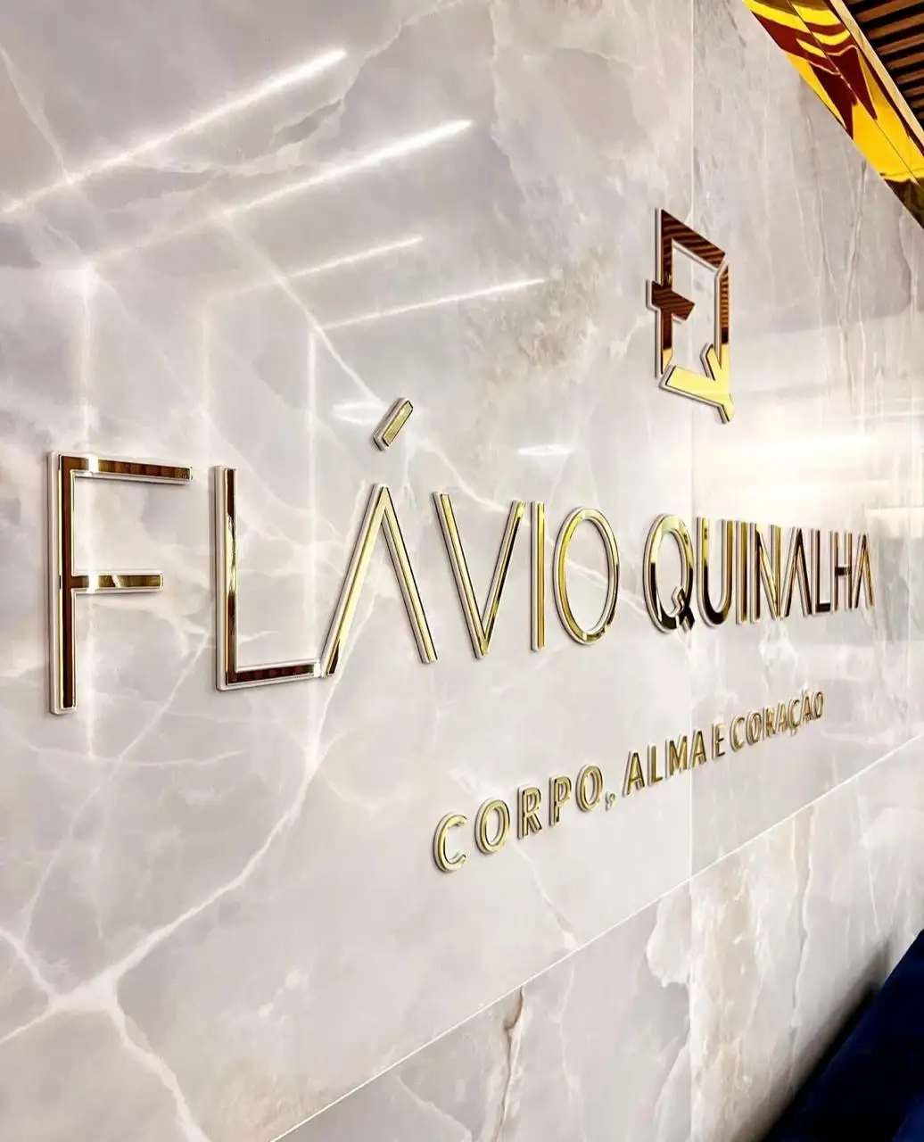 Recepção da clínica com o nome Flávio Quinalha na parede de mármore