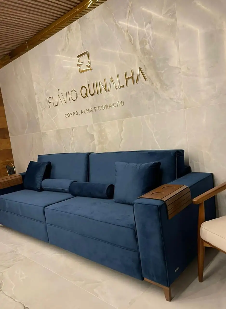 Sala de espera com sofá azul e o monograma FQ na parede